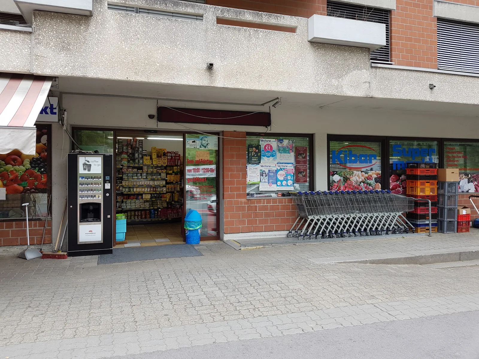 Ladenfront mit Eingang, Einkaufswagenreihe und der Schaufensterbeschriftung Kibar Supermarkt