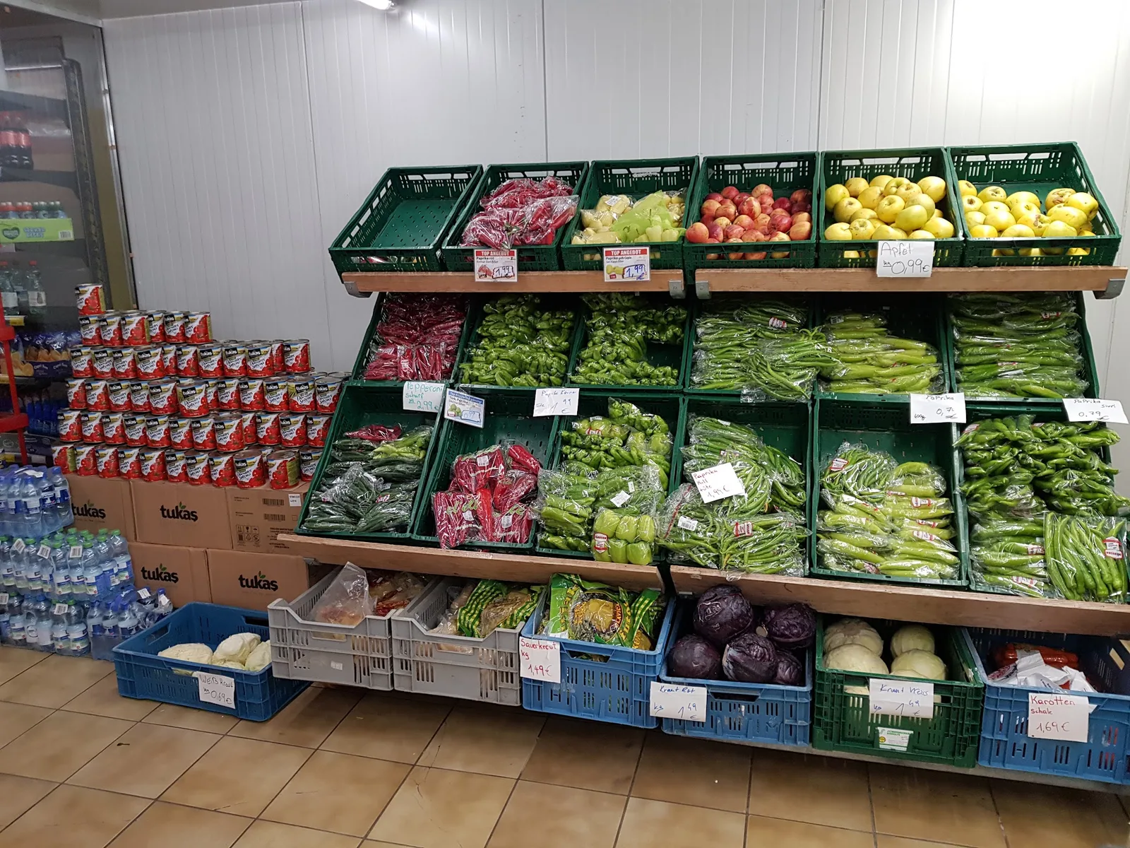 Obst- und Gemüseabteilung im Laden mit Paprika in mehreren Sorten, Kraut und Karotten in Steigen